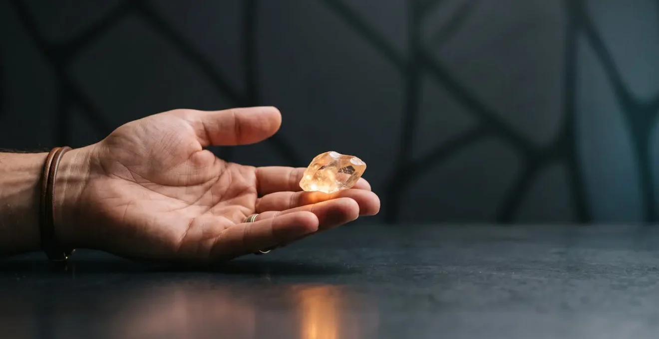 Une main tenant délicatement un fragment de verre lumineux en équilibre sur une surface sombre, symbolisant la tension entre viralité et cohérence de marque