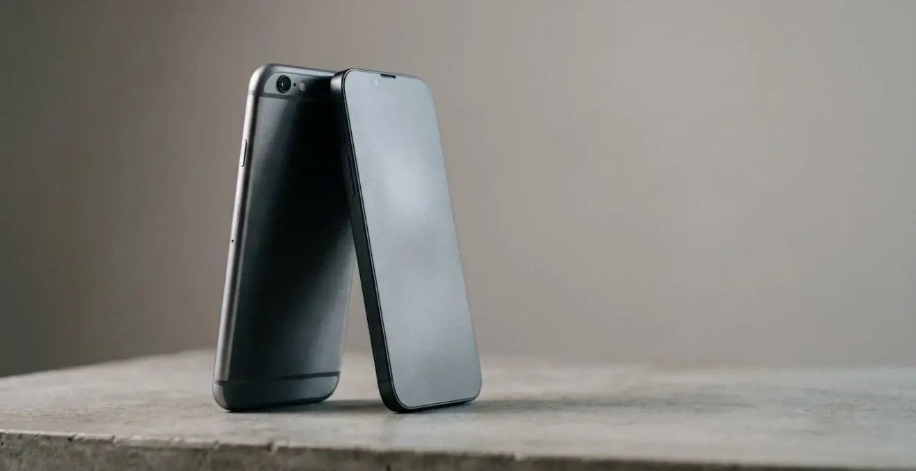 Deux smartphones aux designs distincts posés côte à côte sur une surface neutre, symbolisant l'équilibre entre iOS et Android
