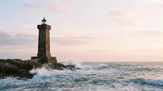 Un phare en pierre resistant fermement aux vagues sur une cote rocheuse, symbolisant un positionnement Google durable face aux fluctuations